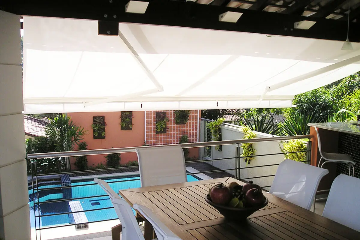 Toldo blanco extendido sobre un balcón con vista a una pileta
