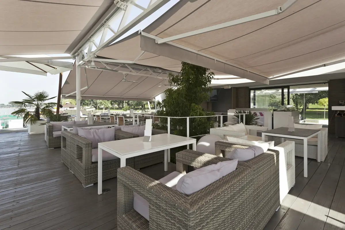 Toldos blancos de brazo invisible sobre un deck con sillones