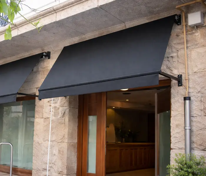 Toldos de lona negra sobre las ventanas de un local con frente de piedra