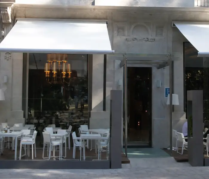 Toldo de lona blanca sobre la entrada de un restaurante con mesas