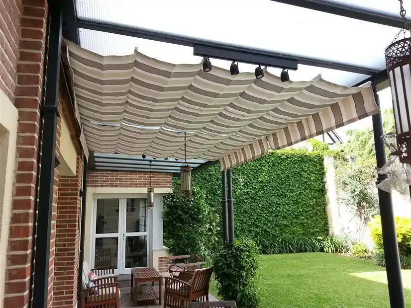 Toldo romano de lona rayada en una galería con jardín vertical