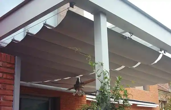 Toldo romano con la lona plegada en ondas bajo una galería