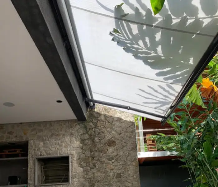 Toldo de brazo invisible visto desde abajo, con la sombra de unas palmeras