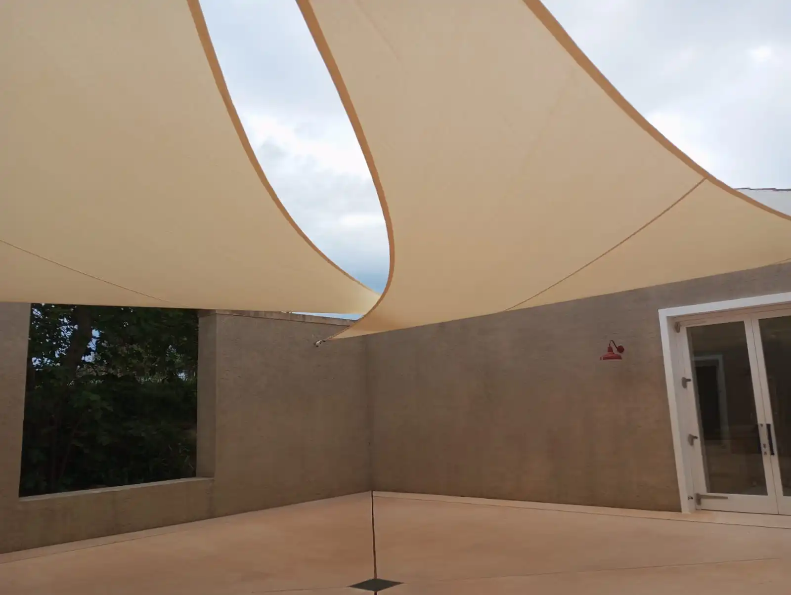 Toldo vela color arena tensado sobre un patio