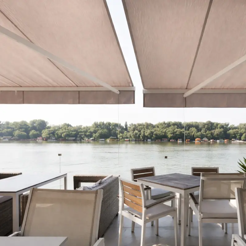 Toldos blancos extendidos sobre las mesas de un bar frente al río