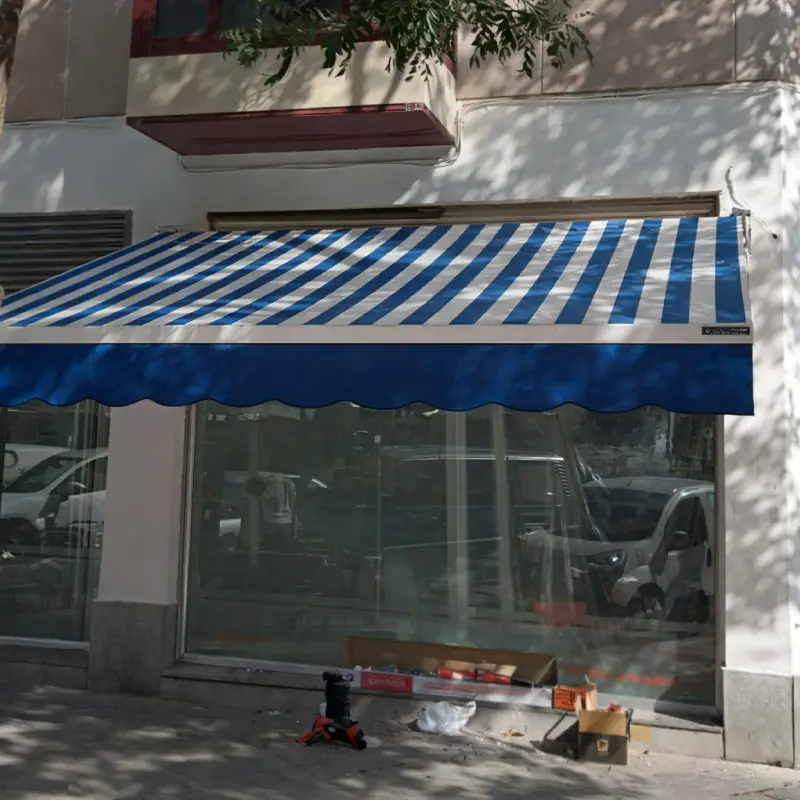 Toldo de lona rayada azul y blanca sobre una vidriera